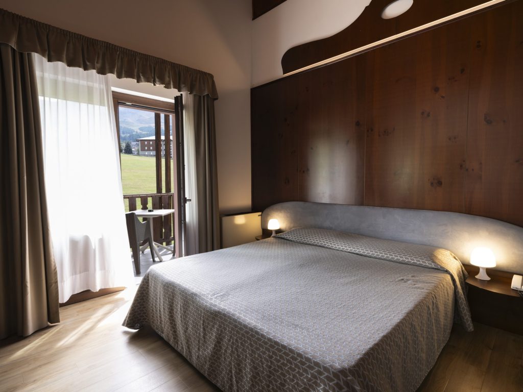 Camera con letto matrimoniale e portafinestra aperta sul balcone