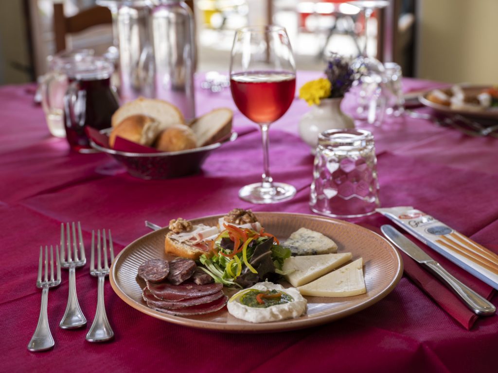 Piatto di salumi e formaggi valdostani con un calice di vino rosso