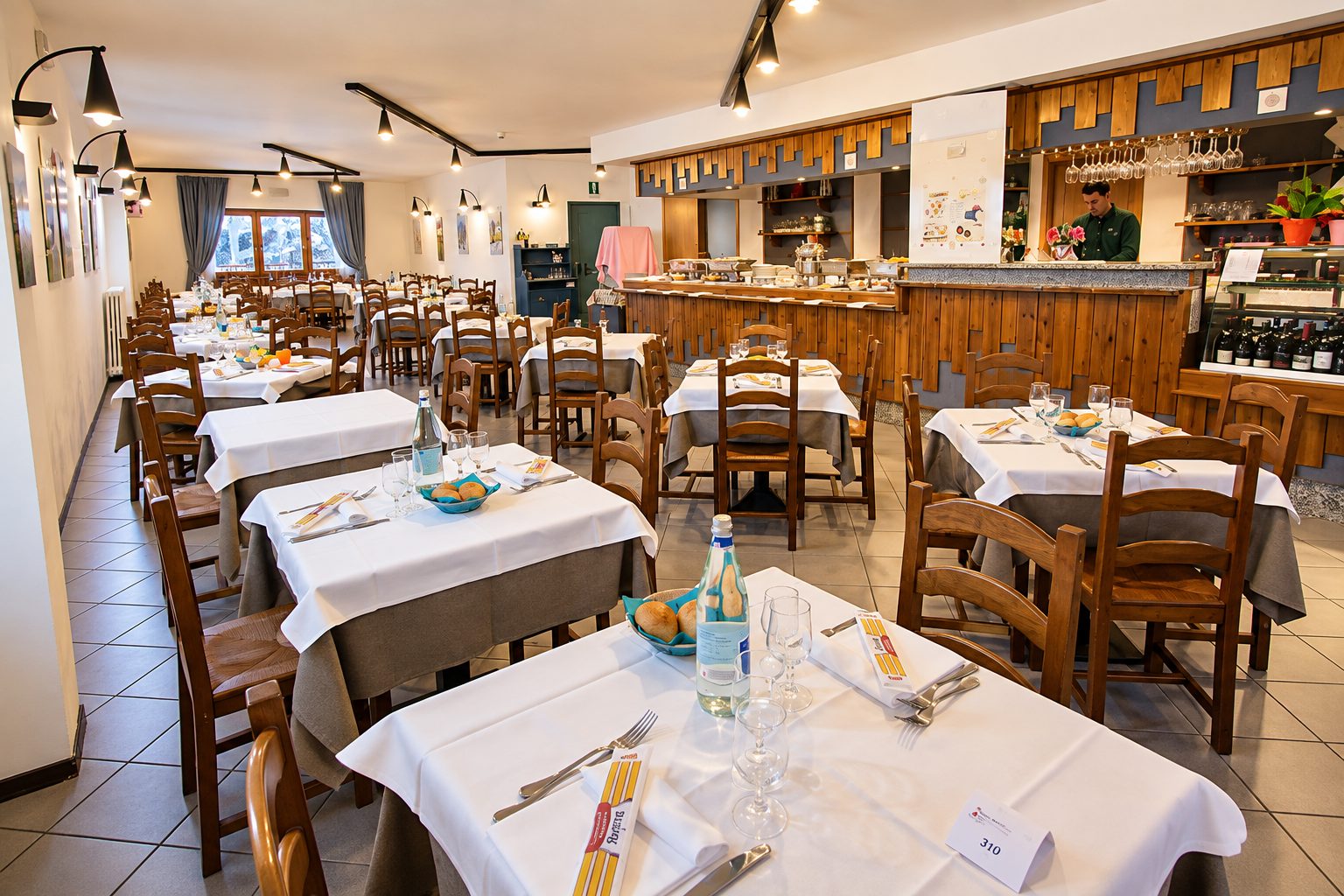 La sala del ristorante con i tavoli apparecchiati e il bancone in legno