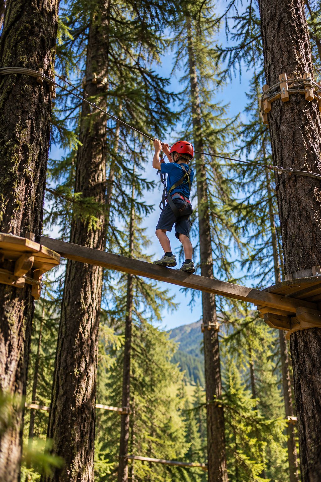 Bambino con il caschetto su un percorso sospeso tra gli alberi del parco avventura
