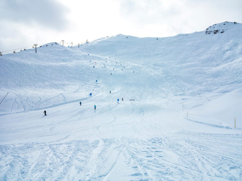 Sciatori sulla pista innevata di Pila, con gli impianti in cima