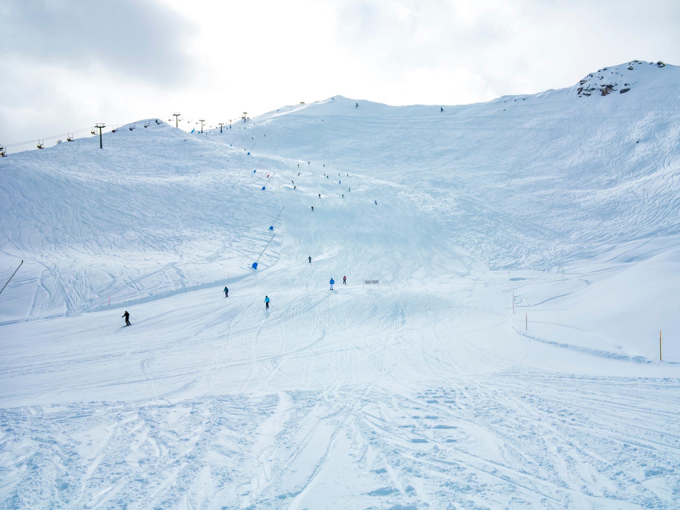 Sciatori sulla pista innevata di Pila, con gli impianti in cima