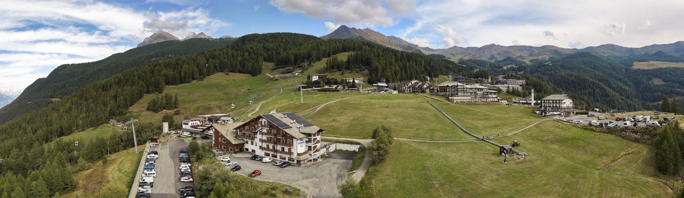 Panorama di Pila d'estate con l'Hotel Etoile de Neige e le montagne della Valle d'Aosta